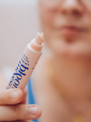 Woman squeezing out a nourishing lip balm from the tube before applying to lips.