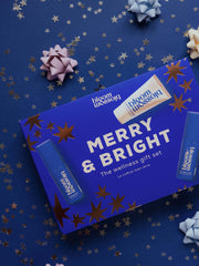 Merry & Bright Wellness gift set on a dark blue background, covered in shiny rose gold stars.