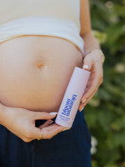 Pregnant woman holding bottle of One Hot Mama Revitalising face & body mist.