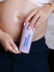 Pregnant woman holding a bottle of Skin to Skin Bump to baby massage oil.
