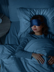 Woman sleeping soundly with a dark blue satin-soft eye mask.