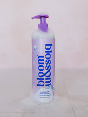 Bottle of shower gel surrounded in soapy bubbles in a shower.